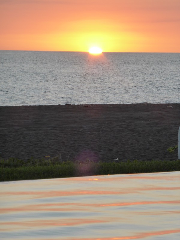 The sun setting into the infinity pool that overlooks the Pacific Ocean