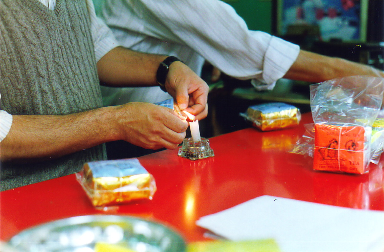 A tea vendor sealing tea packets with a candle