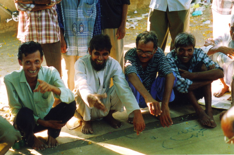 A smiling man throwing the conch shell in a game of Aman Chache