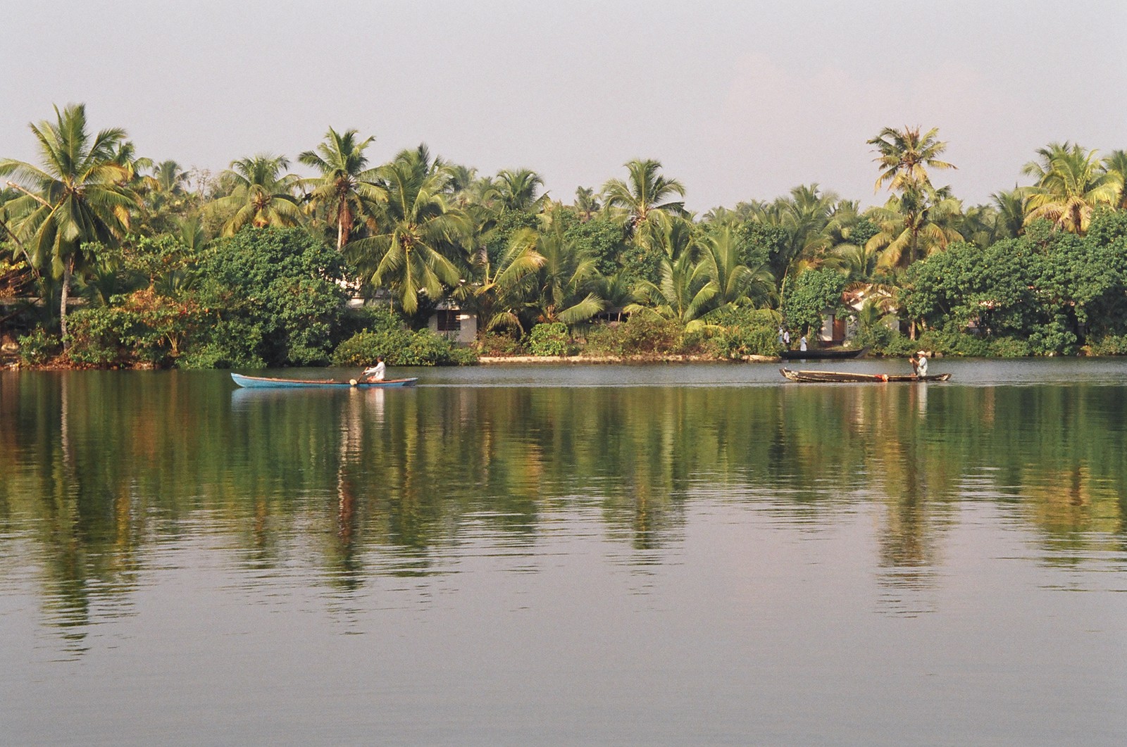 Two men rowing canoes along the backwaters
