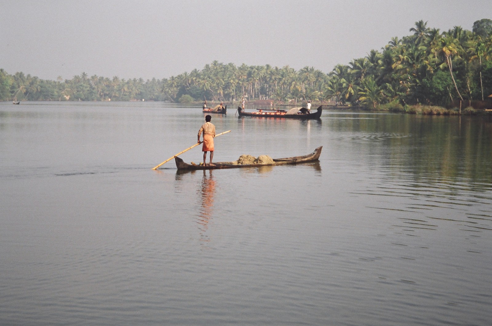 A man punting a canoe filled with sand