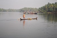 A man punting a canoe filled with sand