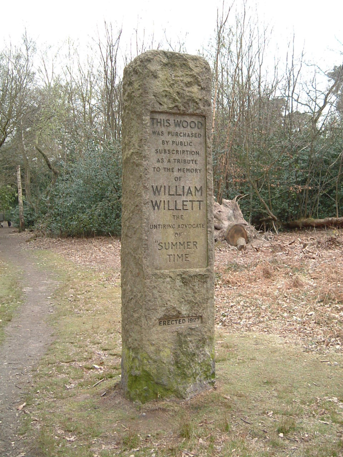 A granite marker, enscribed with the words 'This wood was purchased by public subscription as a tribute to the memory of William Willett, the untiring advocate of 