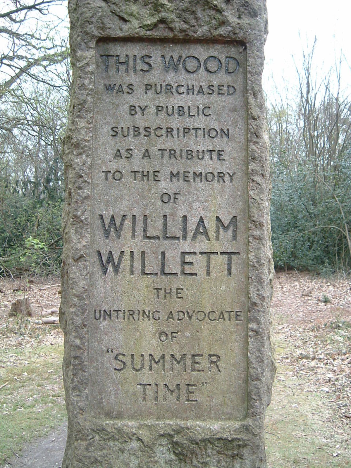 A granite marker, enscribed with the words 'This wood was purchased by public subscription as a tribute to the memory of William Willett, the untiring advocate of 